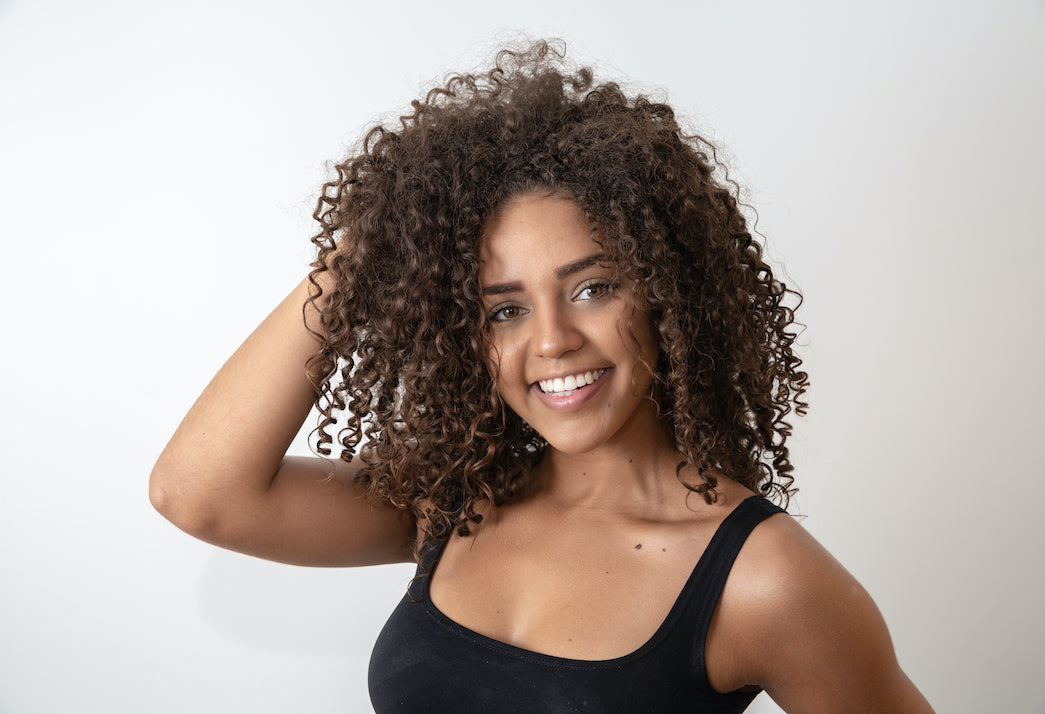 Woman smiling at camera and tousling hair