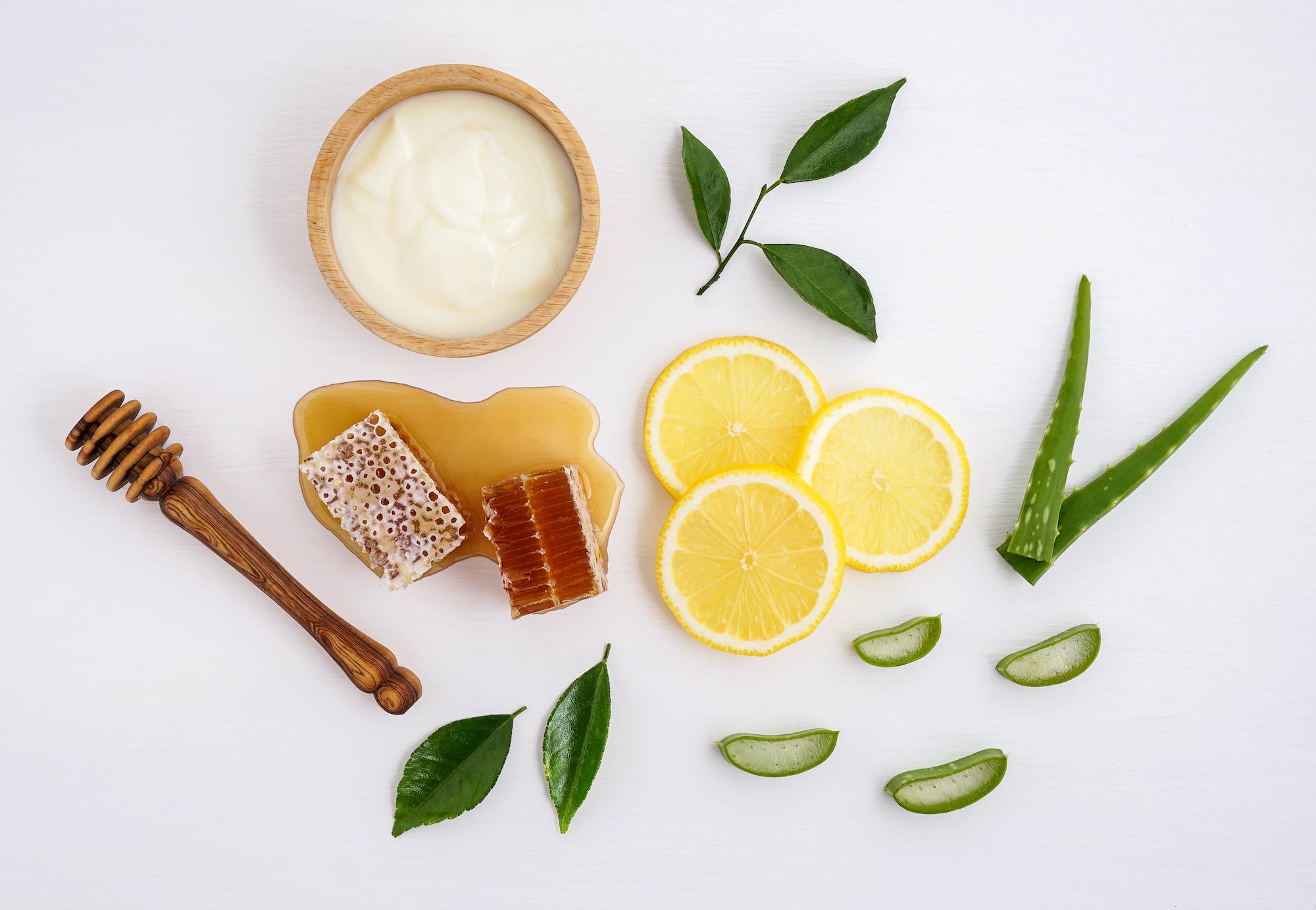 Flatlay image of yogurt, honey, lemon, and aloe vera ingredients. 