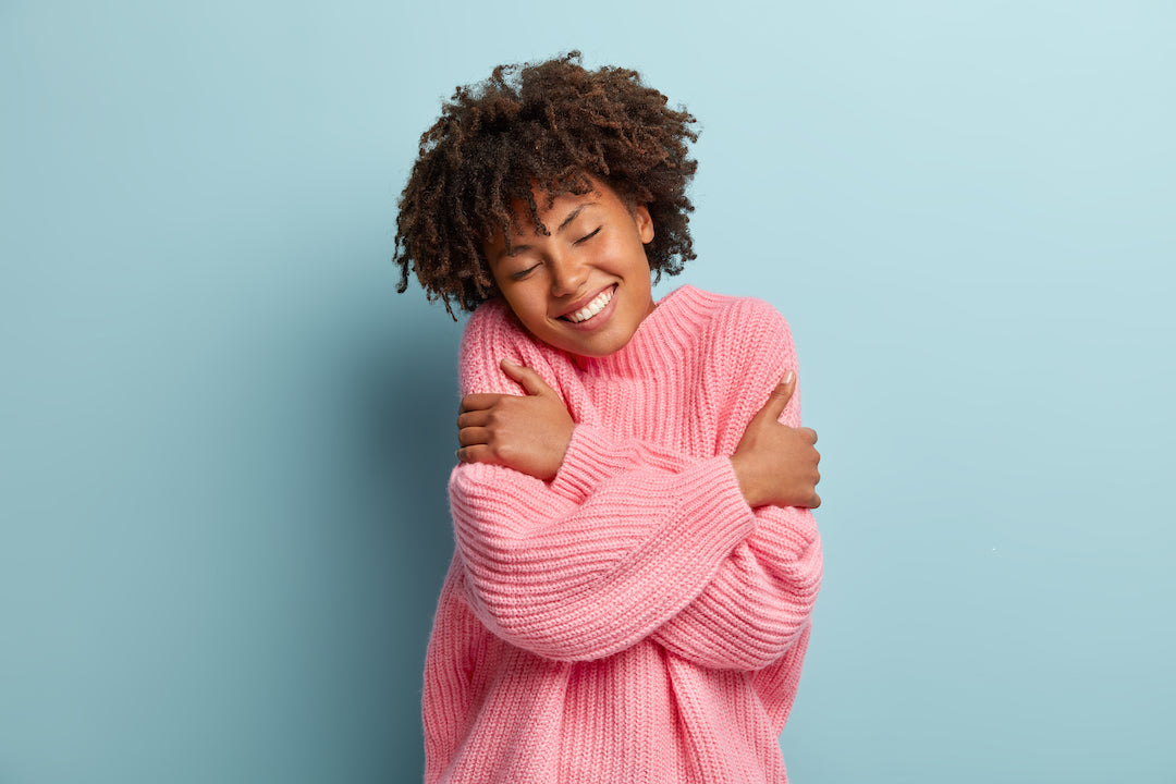 Woman in cozy knit pink sweater hugging self